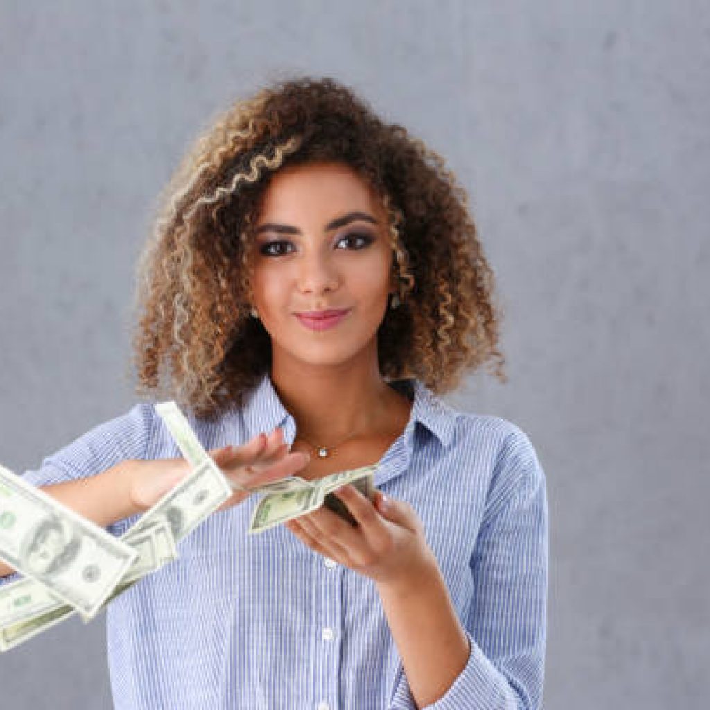 Beautiful black woman portrait. Scattering money notes dollars in fashion vows style curly hair with white locks eye view of the camera
